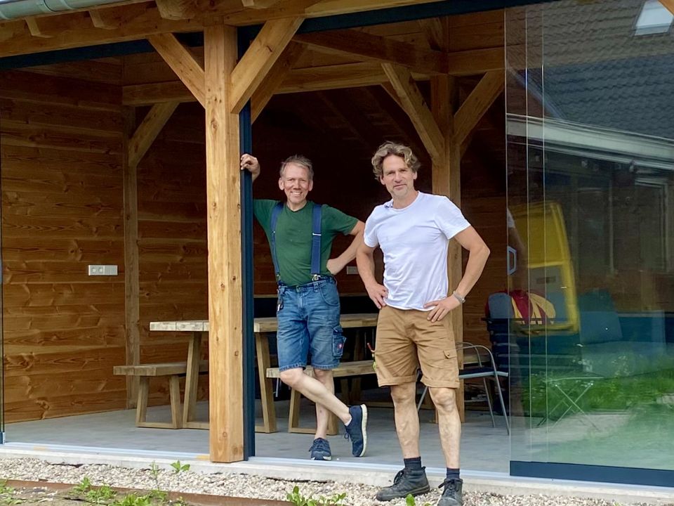 Houten tuinkamer met glazen schuifwanden en pannendak, met de twee makers van Eigen Buiten op de voorgrond
